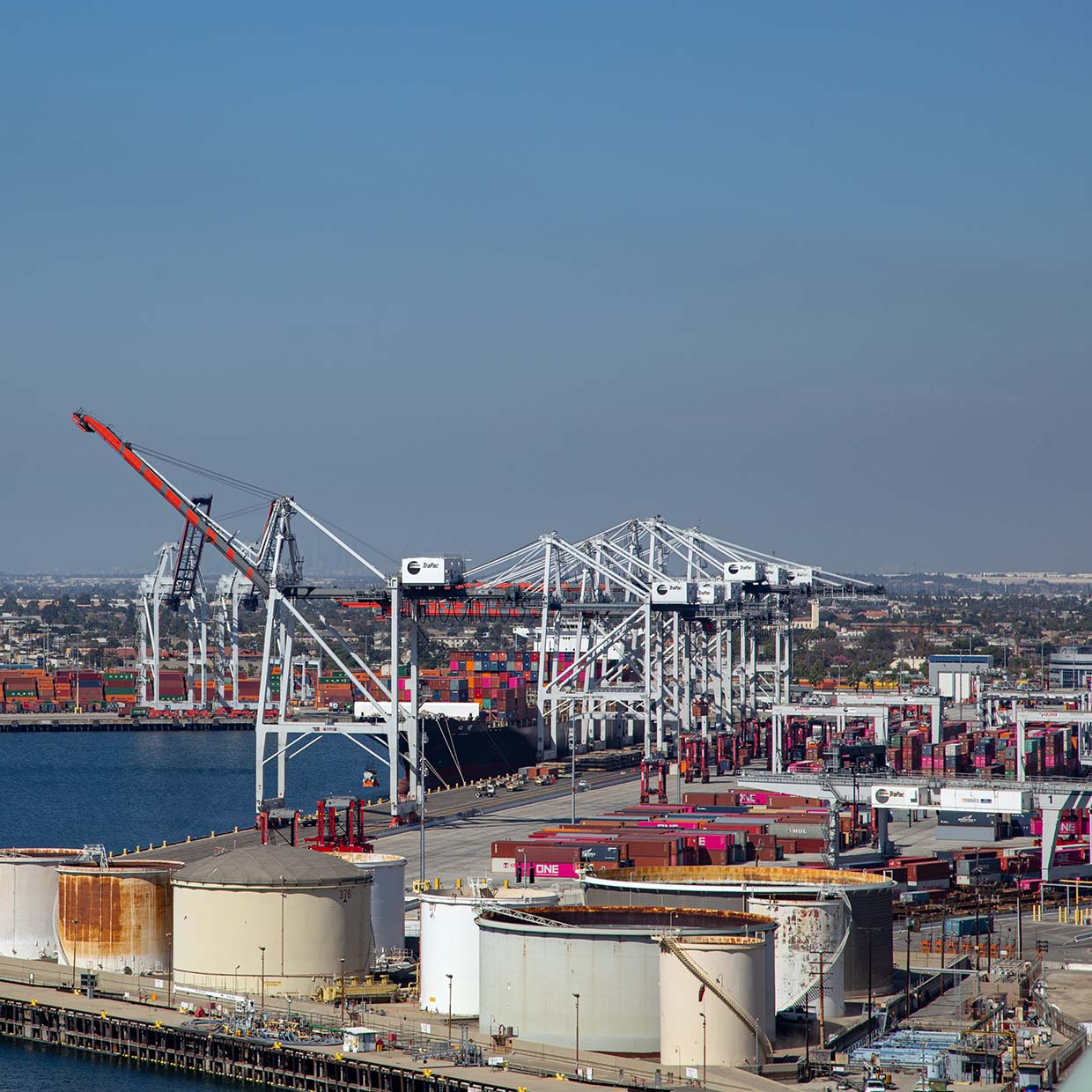 Wide horizon view of the port with tanks in the foreground, cranes and containers in the background